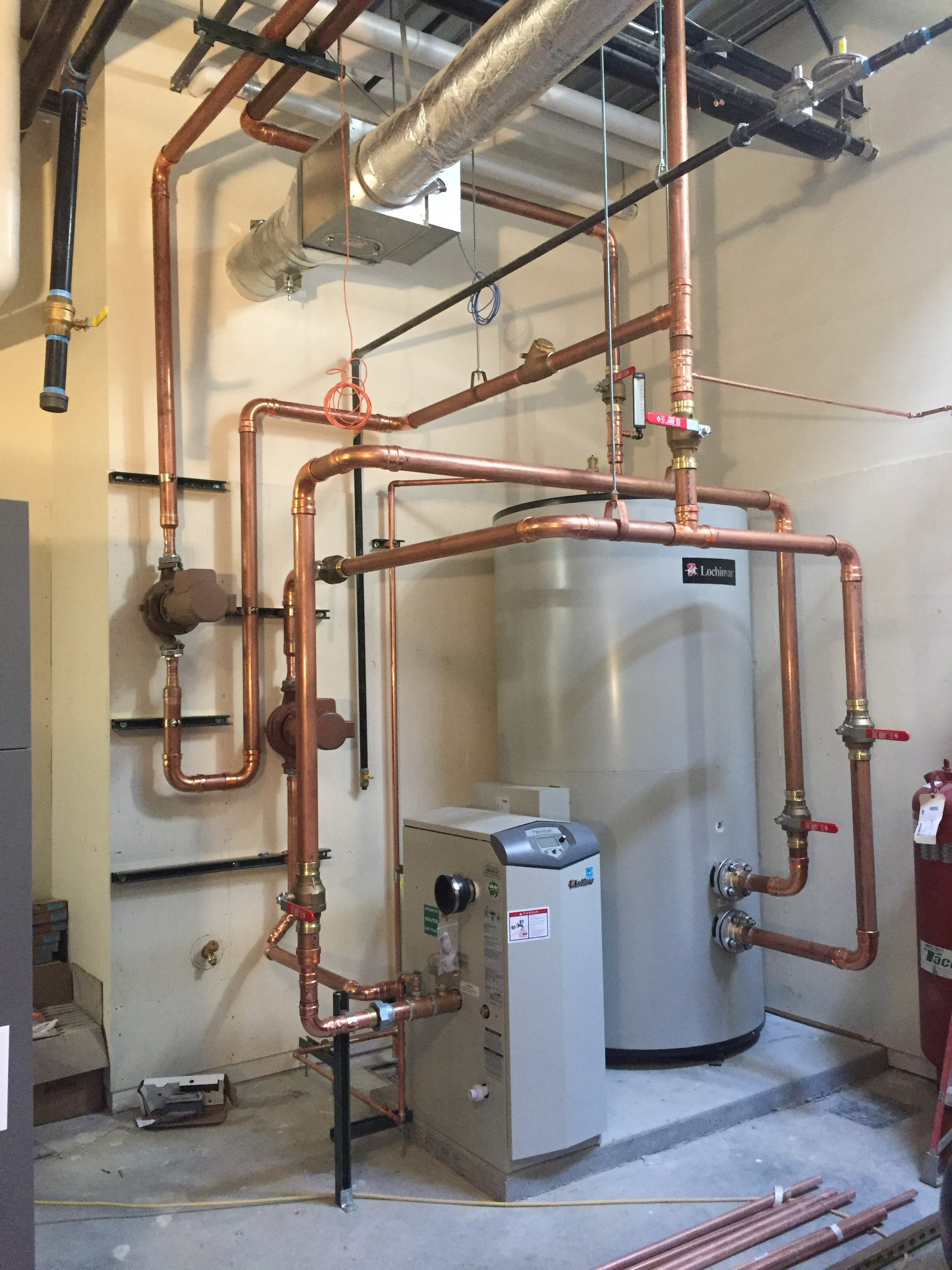 Commercial water heater and boiler room with newly installed copper piping network, valves, circulator pumps and expansion tank, illustrating professional plumbing and mechanical service for residential and commercial installs in Billings, MT